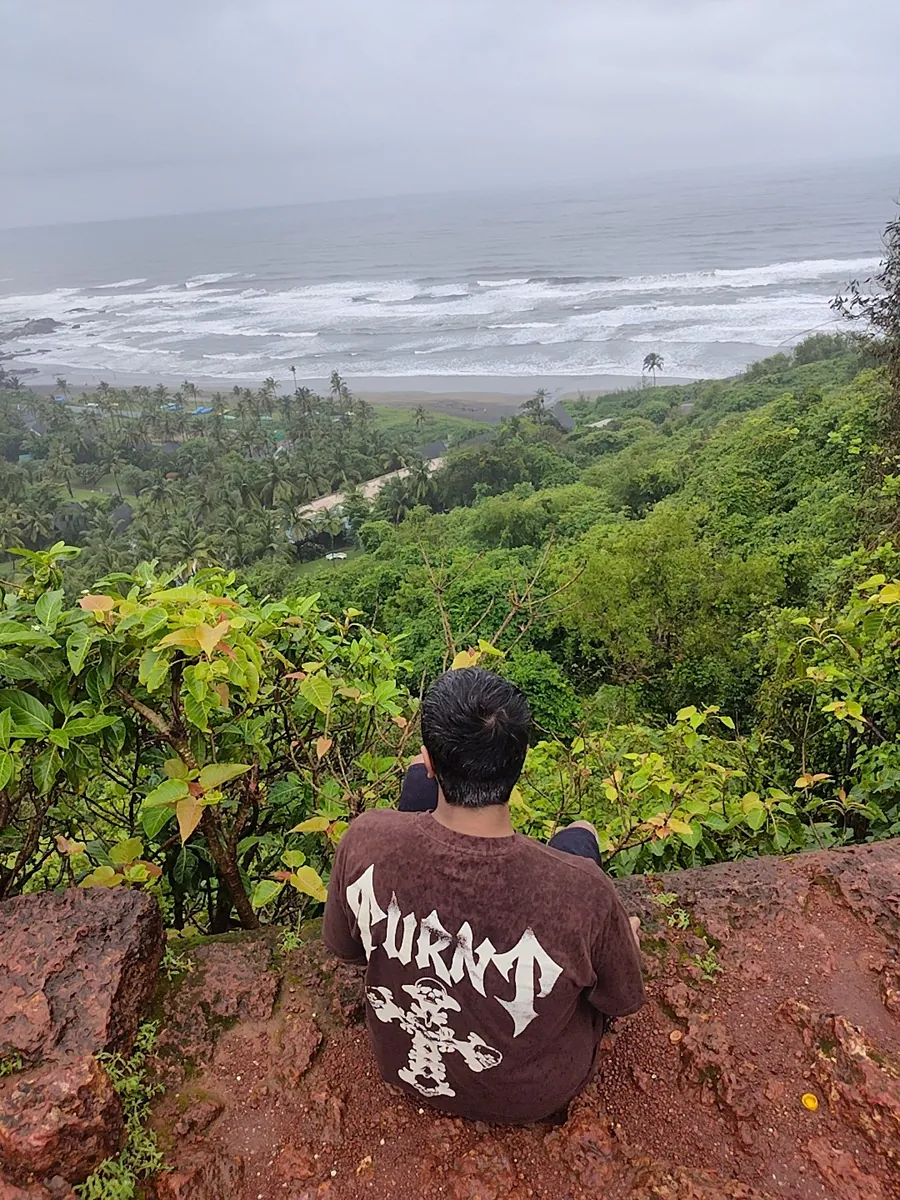 Prithvi from behind, sitting on a laterite ledge above a Goa beach